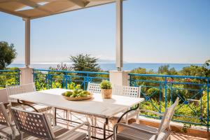 a table and chairs on a balcony with a view of the ocean at Villa Rudi in Trapezaki