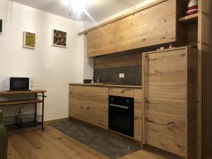 a kitchen with wooden cabinets and a black dishwasher at 017 Trilocale, Pinzolo in Pinzolo