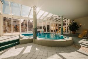 a swimming pool in a building with a large glass ceiling at Hotel Guggenberger in Kleinarl