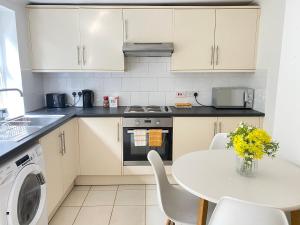 a kitchen with white cabinets and a table with chairs at 4 Bed house sleeps 8 next to Chatham station and Chatham city centre in Chatham +25 photos
