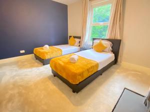a bedroom with two beds with yellow sheets and a window at 4 Bed house sleeps 8 next to Chatham station and Chatham city centre in Chatham
