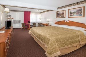 a hotel room with a large bed and a television at Super 8 by Wyndham Laramie in Laramie