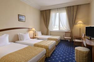 プロブディフにあるRamada by Wyndham Plovdiv Trimontiumのベッド2台とデスクが備わるホテルルームです。