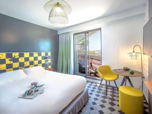 a hotel room with a bed and a table and a window at Mercure Hyères Centre Côte d'Azur in Hyères