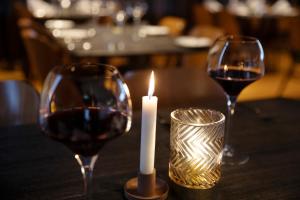 two glasses of wine and a candle on a table at Fosshotel Stykkisholmur in Stykkishólmur