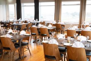 a dining room with tables and chairs and windows at Fosshotel Stykkisholmur in Stykkishólmur