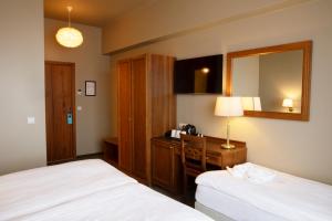 a hotel room with two beds and a desk and a mirror at Fosshotel Stykkisholmur in Stykkishólmur