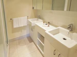 a white bathroom with a sink and a mirror at Oaks Melbourne on Lonsdale Suites in Melbourne