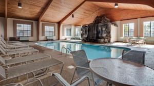 une piscine avec des chaises et des tables dans un bâtiment dans l'établissement Best Western Lapeer Inn, à Lapeer