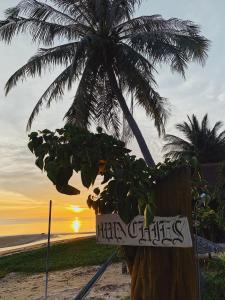 een bord op een strand met een palmboom bij Munchies Bungalows in Baan Tai