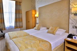 a hotel room with two beds and a desk at Best Western York House Hotel in Eastbourne