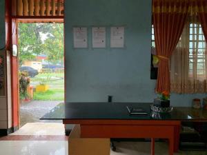 einen Schreibtisch in einem Zimmer mit einem großen Fenster in der Unterkunft OYO 90770 Wisma Rima Melati in Tolo