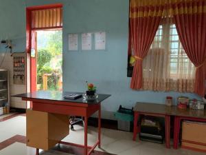 eine Küche mit einem Schreibtisch, einem Tisch und einem Fenster in der Unterkunft OYO 90770 Wisma Rima Melati in Tolo