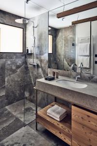a bathroom with a sink and a glass shower at Falkensteiner Hotel Kronplatz - The Leading Hotels of the World in Brunico