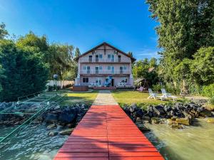 a house with a red boardwalk leading into the water at Zöldpart Villa in Balatonszárszó