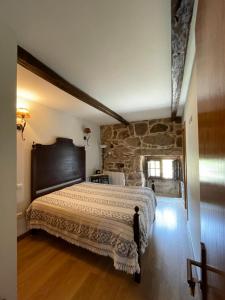 a bedroom with a large bed with a stone wall at Casa D'Campo Ferreira in Pitões das Júnias