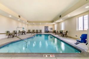 a pool in a hotel room with chairs and tables at Comfort Inn & Suites Salina North in Salina