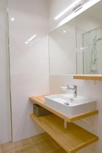 a white bathroom with a sink and a mirror at TATRYSTAY Apartment Sankt Bernard in Nový Smokovec
