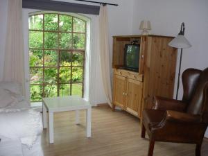 a living room with a bed and a tv and a window at Little Rose Cottage - Urlaub unter Reet zwischen den Meeren in Börm