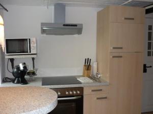 a kitchen with a stove top oven next to a microwave at Little Rose Cottage - Urlaub unter Reet zwischen den Meeren in Börm +4 photos