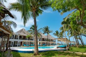 un complexe avec piscine et palmiers dans l'établissement Nest Style Beach Hotel Zanzibar, à Makunduchi