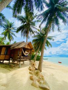 a hammock and two palm trees on a beach at Castaway Beach Bungalows in Srithanu