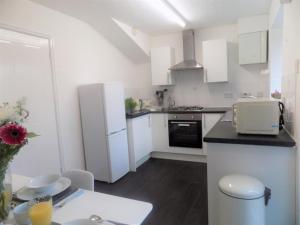 a kitchen with white cabinets and a white refrigerator at Hive Close in Stockton-on-Tees