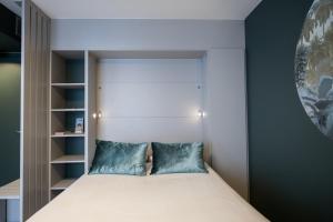 a small bedroom with a bed with blue pillows at Le Richan - 21 m au coeur de la Croix-Rousse climatisé in Lyon