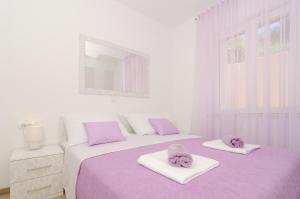 - une chambre avec 2 lits dotés de draps violets et d'un miroir dans l'établissement Apartments Marmo, à Mlini