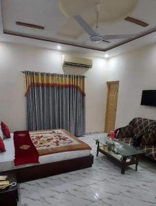 a bedroom with a bed and a couch and a table at Decent Lodge Hotel Garden Town in Lahore