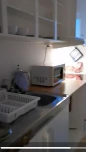 a kitchen counter with a sink and a microwave at Kveldsol Apartments in Havøysund