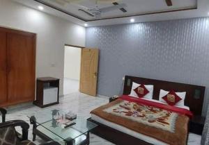 a bedroom with a bed and a table in it at Decent Lodge Hotel Garden Town in Lahore
