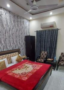 a bedroom with a large bed with a red blanket at Decent Lodge Hotel Garden Town in Lahore