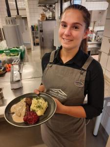 a woman holding a plate of food in a kitchen at Hafjell Hotell in Hafjell