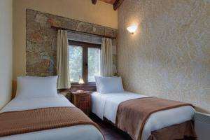 two beds in a room with a stone wall at Parnassus Dreamwood Chalet in Eptalofos