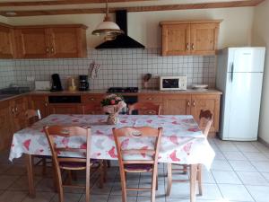 a kitchen with a table with chairs and a white refrigerator at chantacalme in Montboissier