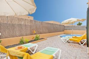 un patio con sillas, una sombrilla y una piscina en La Casa del Sol l by Best Holidays Fuerteventura, en Corralejo