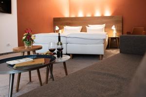 アスペルクにあるHotel Adler Aspergのベッド1台とワイン2杯が備わるホテルルームです。