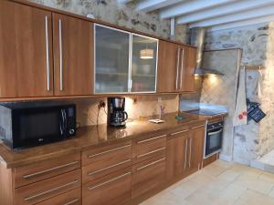 eine Küche mit Holzschränken und einer schwarzen Mikrowelle in der Unterkunft GITE D'HAUTEVESNES in Hautevesnes