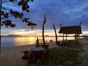 a hut on the beach with the sunset in the background at MK AL-ATTAS HOMESTAY - KUALA BESUT in Kampong Nail