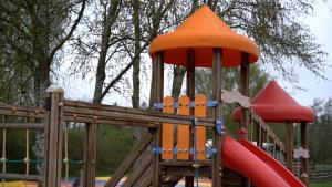 une aire de jeux en bois avec toboggan rouge et toboggan rouge dans l'établissement Bygholm Camping, à Vesløs