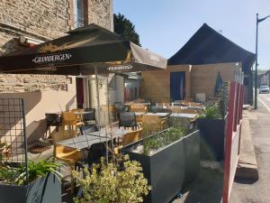 ein Restaurant mit Tischen, Stühlen und einem Sonnenschirm in der Unterkunft Hotel au Pont d'Anjou in La Guerche-de-Bretagne