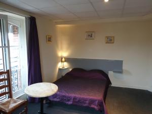 um quarto com uma cama, uma mesa e uma janela em Hotel au Pont d'Anjou em La Guerche-de-Bretagne