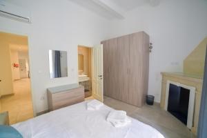 a bedroom with a white bed and a fireplace at CA1- City Central Apartment 1 in Valletta