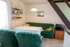 a living room with a table and two green chairs at Ferienhaus Boddenkieker in Freest