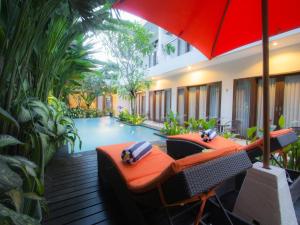 a hotel patio with a pool and a red umbrella at The Pavilion Hotel Kuta in Kuta