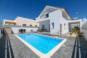 a villa with a swimming pool in front of a house at Villa Olivia in Xylophaghou