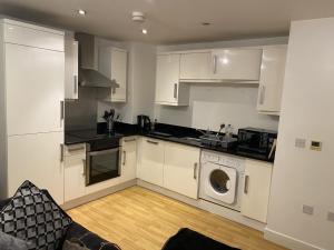 a kitchen with white cabinets and a washing machine at Westpoint in Derby