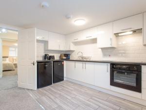 a kitchen with white cabinets and black appliances at Dartford Luxurious Apartment in Dartford