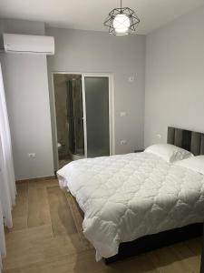 a white bedroom with a large bed and a mirror at Eagle’s Nest in Shkodër